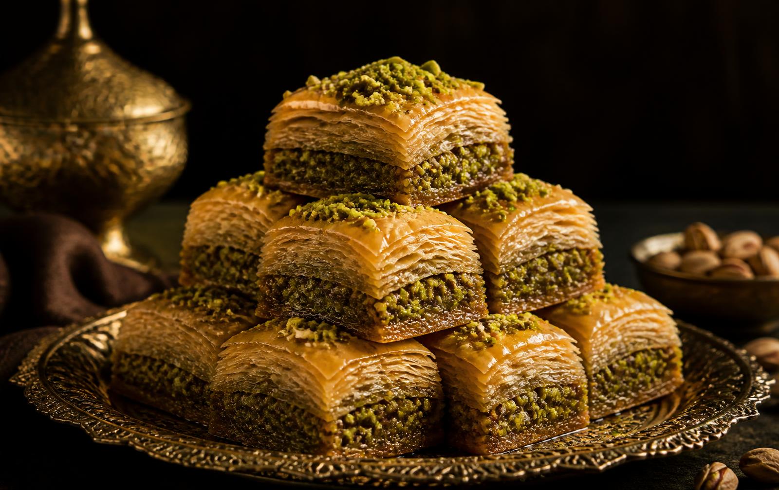 Golden Lebanese baklava topped with pistachio on a brass tray